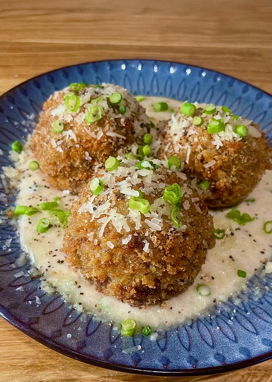 Red wine braised beef short rib croquettes with spiced bechamel topped with garlic scapes